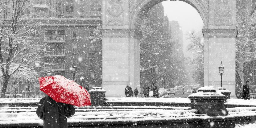 Photo of NYC's Washington Square Park in winter with snow and person with red umbrella